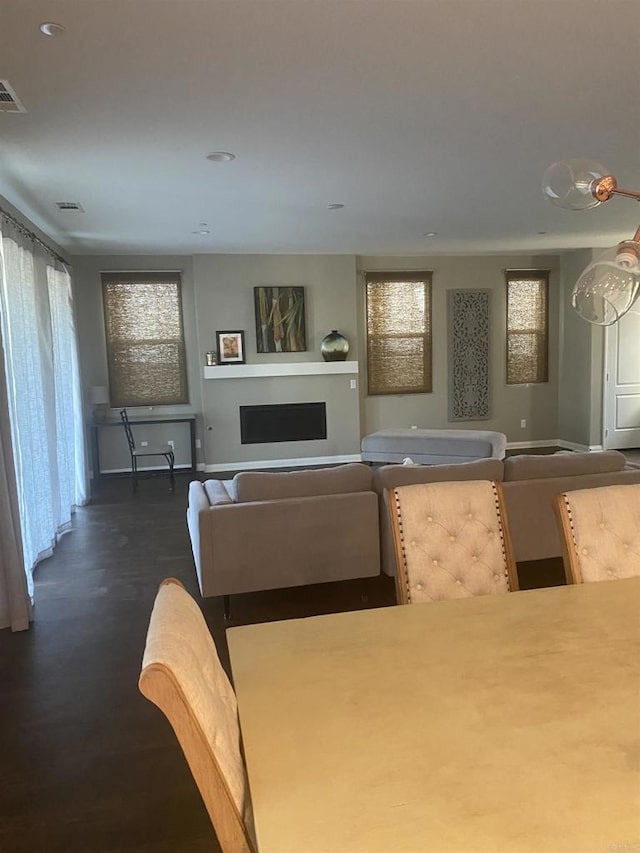 living room featuring dark wood-style flooring, visible vents, and a fireplace