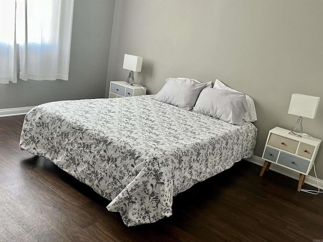 bedroom with dark wood-style flooring and baseboards