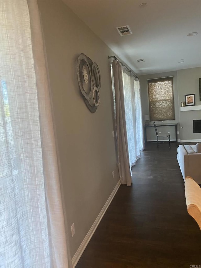 corridor featuring baseboards, visible vents, and dark wood-style flooring