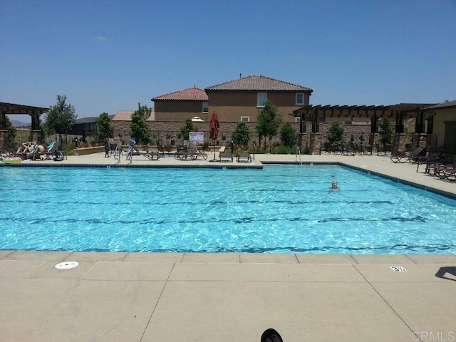 community pool featuring fence and a patio