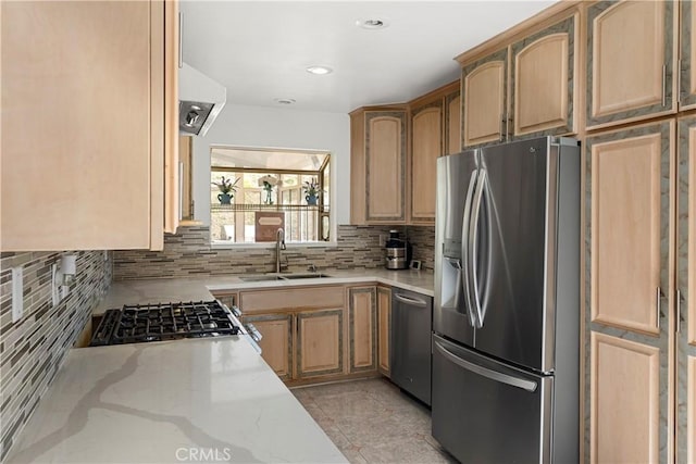 kitchen with light stone counters, decorative backsplash, appliances with stainless steel finishes, light brown cabinets, and a sink