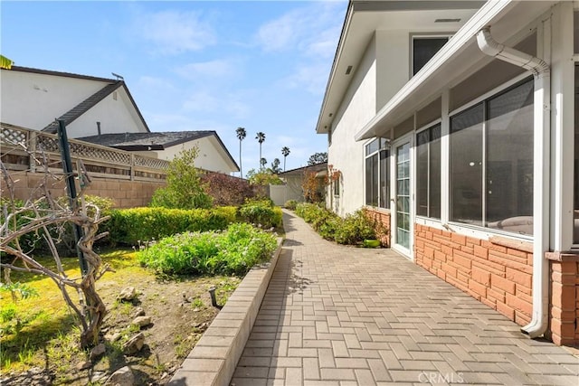 view of side of property with a patio, fence, and stucco siding