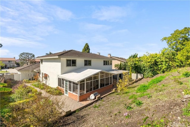 back of property with a sunroom and stucco siding