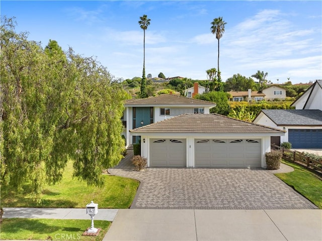 view of front of house featuring a front lawn, decorative driveway, an attached garage, and a tile roof