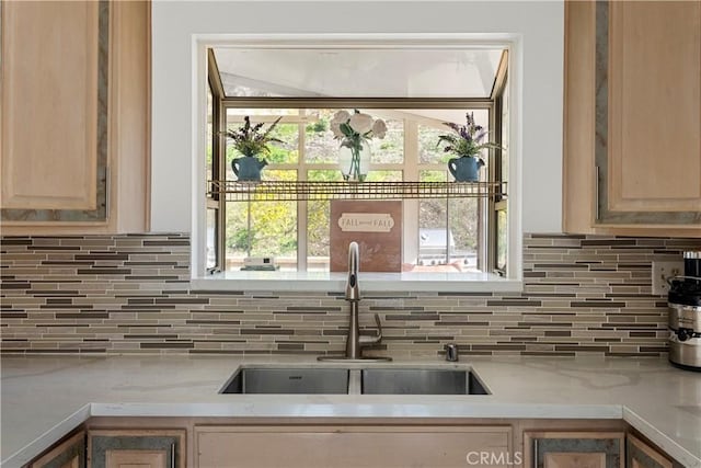 kitchen with tasteful backsplash, light countertops, a sink, and light brown cabinets