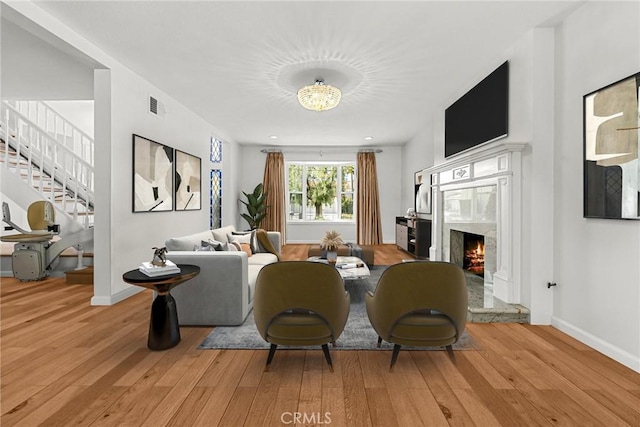 sitting room featuring light wood finished floors, stairs, visible vents, and a high end fireplace