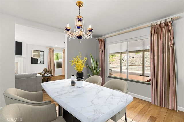 dining room with baseboards, plenty of natural light, light wood-style flooring, and a notable chandelier