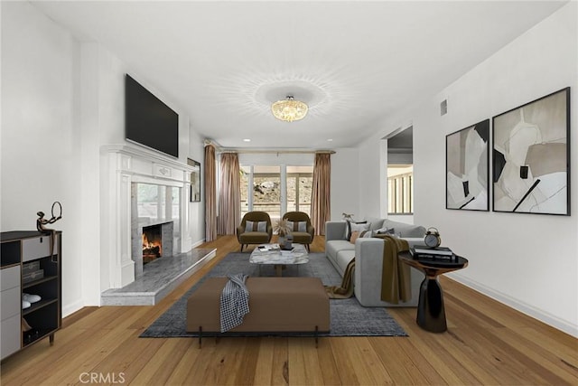 living room featuring visible vents, a fireplace, hardwood / wood-style flooring, and baseboards