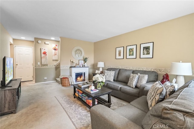 living room featuring a lit fireplace, baseboards, and light colored carpet