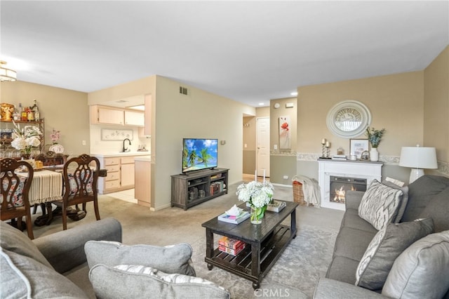 living room with light colored carpet, visible vents, a glass covered fireplace, and baseboards