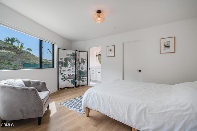 bedroom with light wood-type flooring and ensuite bathroom