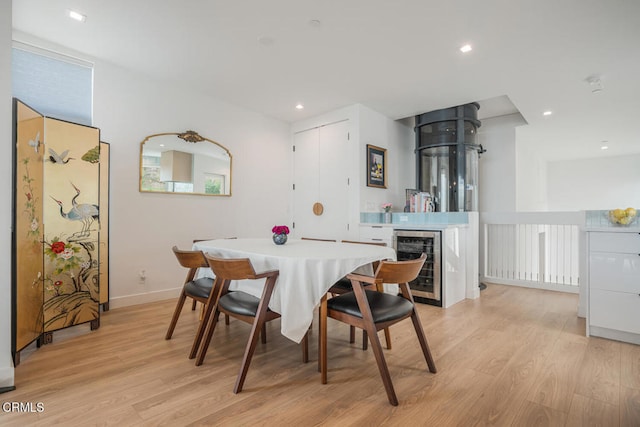 dining room featuring light wood-style floors, wine cooler, baseboards, and recessed lighting