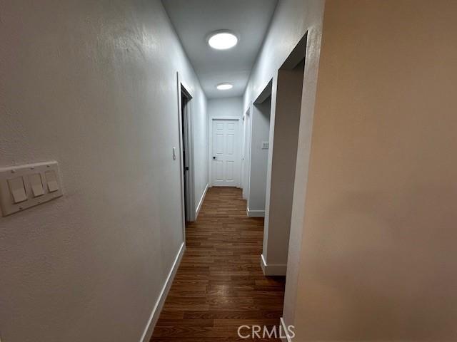 hall with baseboards and dark wood-type flooring