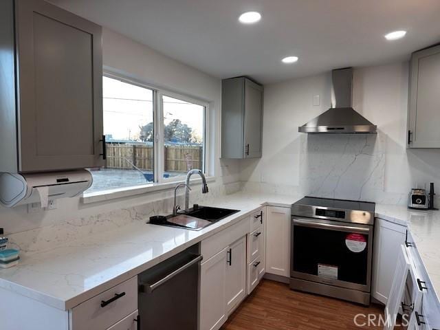 kitchen with light stone counters, electric range, a sink, wall chimney range hood, and dishwashing machine