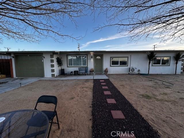 single story home with driveway, an attached garage, and stucco siding