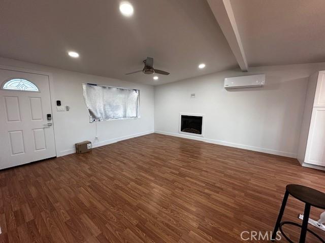 unfurnished living room featuring dark wood-type flooring, recessed lighting, a wall unit AC, and a fireplace