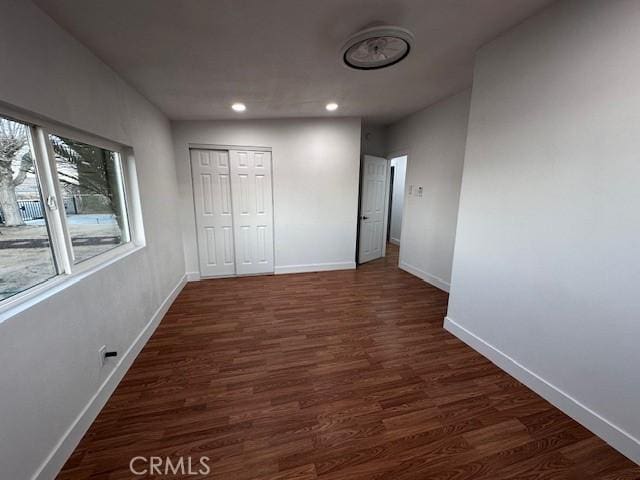 unfurnished bedroom with a closet, recessed lighting, dark wood-style flooring, and baseboards