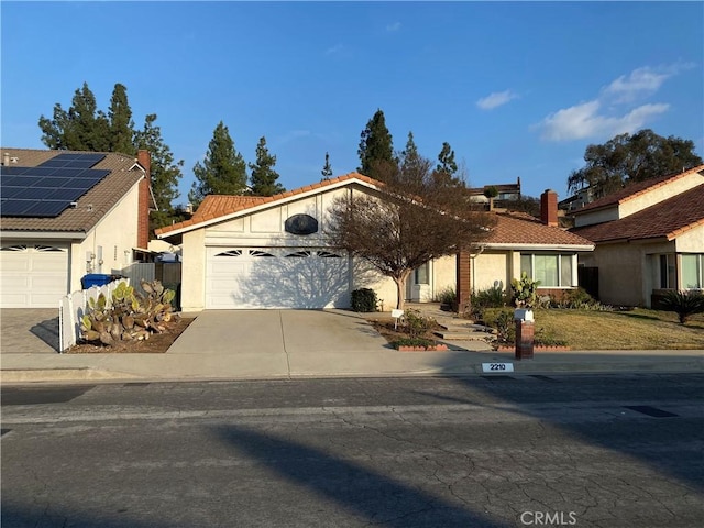 view of front of house featuring a garage, stucco siding, concrete driveway, and a tiled roof