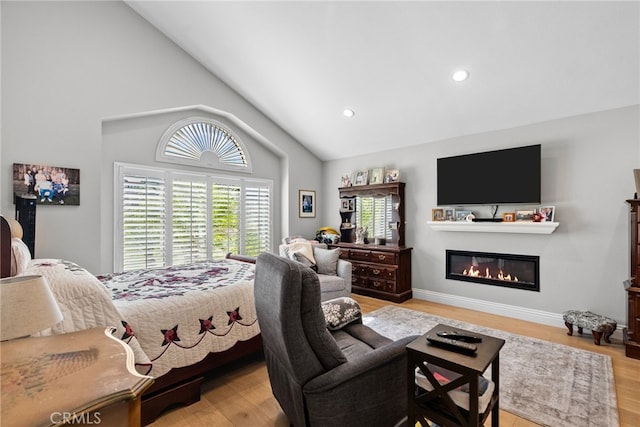 bedroom featuring recessed lighting, a glass covered fireplace, vaulted ceiling, wood finished floors, and baseboards