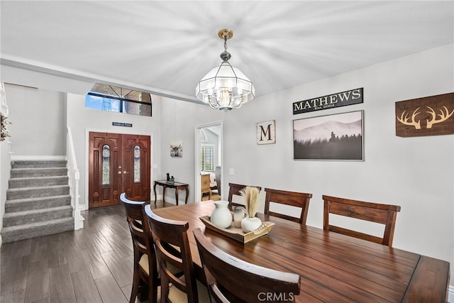 dining room with a healthy amount of sunlight, a notable chandelier, stairs, and dark wood-style flooring