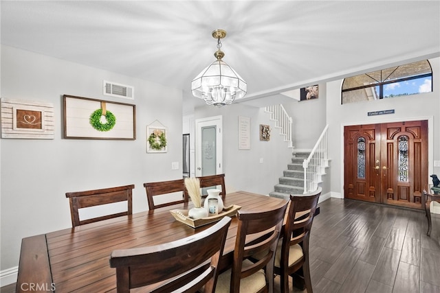 dining space featuring a chandelier, visible vents, baseboards, stairway, and dark wood-style floors