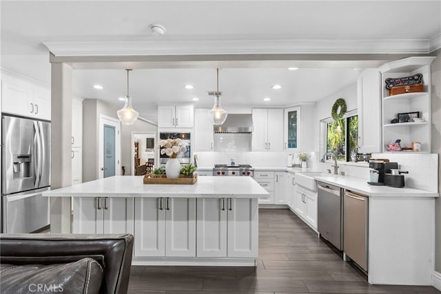 kitchen featuring decorative backsplash, appliances with stainless steel finishes, a center island, wall chimney range hood, and a sink