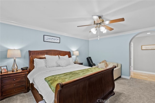 carpeted bedroom featuring ornamental molding, arched walkways, ceiling fan, and baseboards