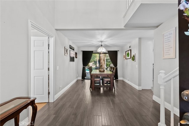 dining area with stairs, dark wood-type flooring, baseboards, and an inviting chandelier