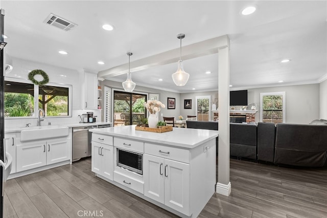 kitchen with dark wood finished floors, crown molding, visible vents, appliances with stainless steel finishes, and a sink