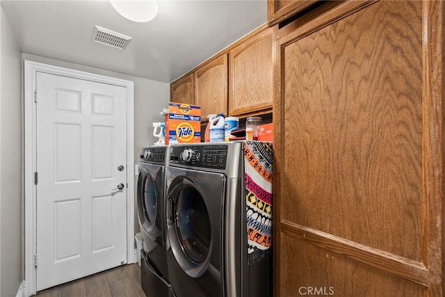 laundry area with washing machine and dryer, cabinet space, dark wood finished floors, and visible vents