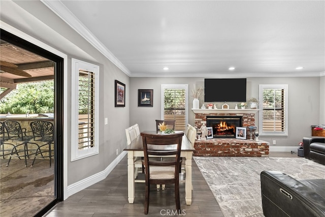 dining room with crown molding, a fireplace, baseboards, and wood finished floors