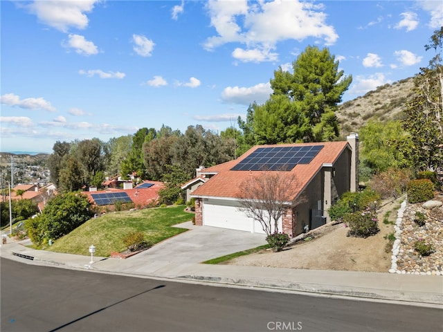 view of front of home featuring a garage, solar panels, and concrete driveway