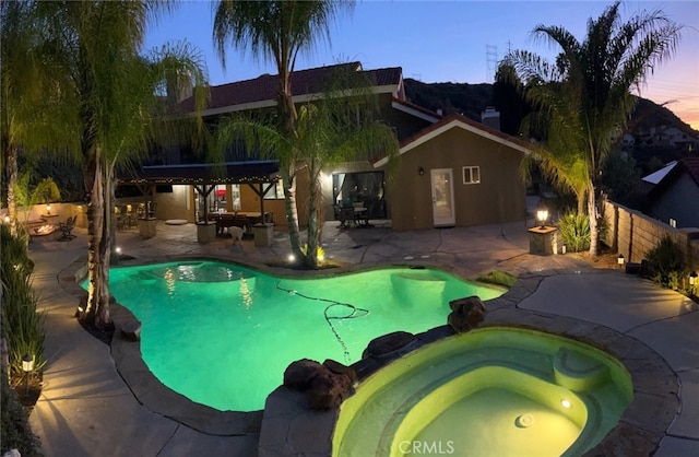 view of pool featuring a patio area, a pool with connected hot tub, and fence