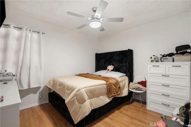 bedroom with light wood finished floors, baseboards, a ceiling fan, and a textured ceiling