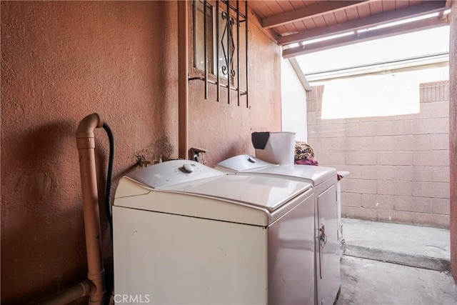 laundry area featuring concrete block wall, laundry area, a textured wall, and washing machine and clothes dryer