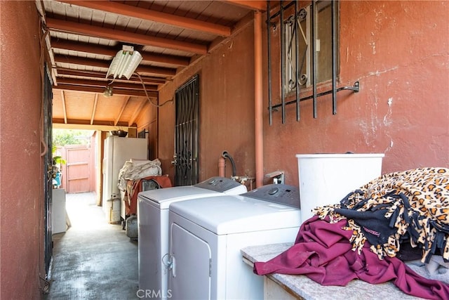 laundry room featuring laundry area, wood ceiling, a textured wall, and washing machine and clothes dryer