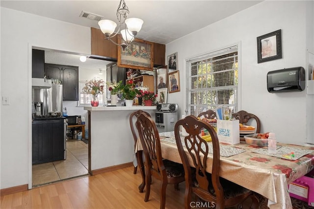 dining room with a chandelier, baseboards, visible vents, and light wood-style floors