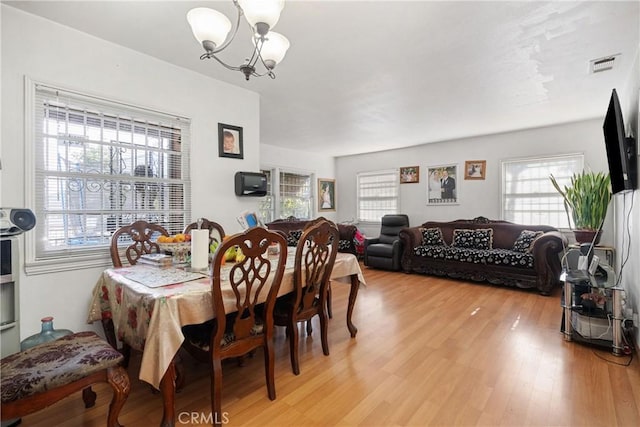 dining space featuring light wood finished floors, visible vents, and an inviting chandelier