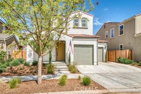 mediterranean / spanish home with stucco siding, fence, a garage, driveway, and a tiled roof