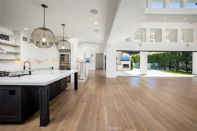 kitchen with white cabinets, open floor plan, light countertops, light wood-type flooring, and recessed lighting