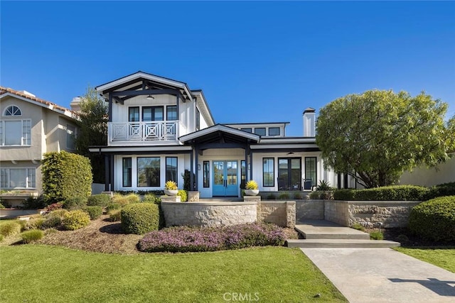 view of front facade with a front yard and a balcony