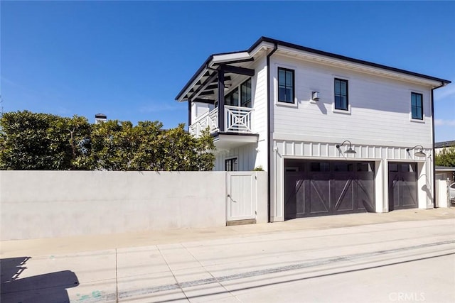 view of home's exterior with a balcony, driveway, a garage, and board and batten siding