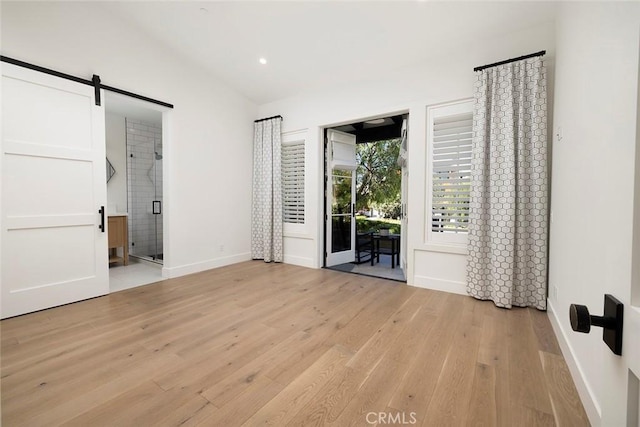 spare room with light wood-type flooring, recessed lighting, baseboards, and a barn door