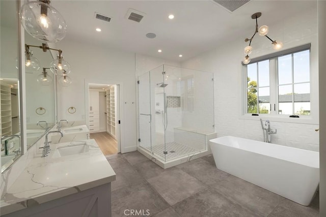 full bath featuring a freestanding bath, double vanity, a sink, and a shower stall