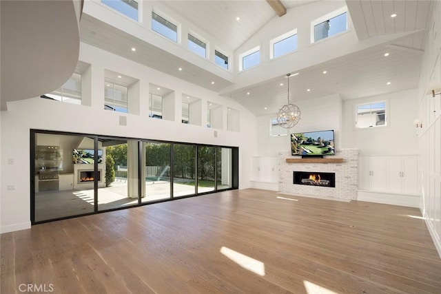 unfurnished living room with a healthy amount of sunlight, a warm lit fireplace, and wood finished floors