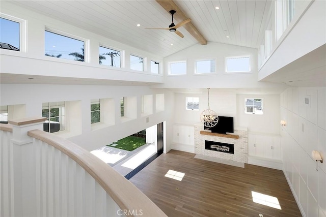 unfurnished living room featuring beam ceiling, a fireplace, wood finished floors, high vaulted ceiling, and wooden ceiling