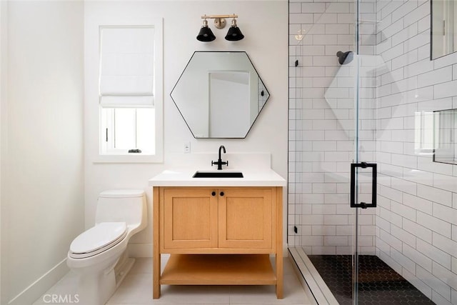 bathroom with vanity, a shower stall, toilet, and baseboards