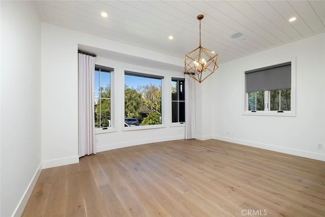 unfurnished room featuring a chandelier, light wood finished floors, and plenty of natural light