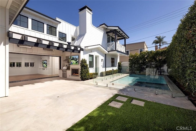 back of house featuring a fenced in pool, a patio, a balcony, a chimney, and board and batten siding