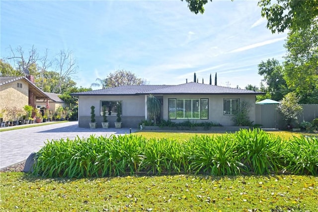 view of front facade with decorative driveway, a front lawn, and stucco siding